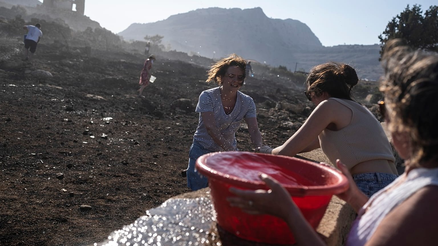 German tourists together with local residents try to extinguish a fire, near the seaside resort of Lindos, on the Aegean Sea island of Rhodes, southeastern Greece, on Monday.