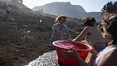 German tourists together with local residents try to extinguish a fire, near the seaside resort of Lindos, on the Aegean Sea island of Rhodes, southeastern Greece, on Monday.