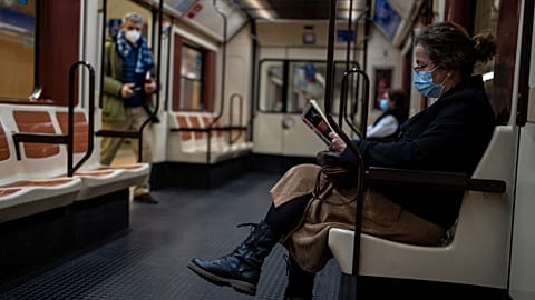A woman wearing a face mask reads a book on a subway in Madrid, Spain, Thursday, Jan. 20, 2022.