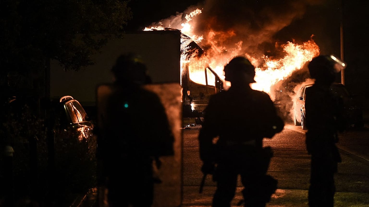 Anti-riot police officers watch a truck burn in Nantes days after a 17-year-old was killed by police in Nanterre.