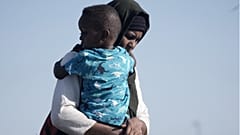 سودانية تم إجلاؤها تحمل ابنها أثناء وصولهما إلى ميناء جدة، المملكة العربية السعودية، 4 مايو 2023.