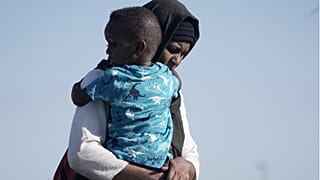 سودانية تم إجلاؤها تحمل ابنها أثناء وصولهما إلى ميناء جدة، المملكة العربية السعودية، 4 مايو 2023.