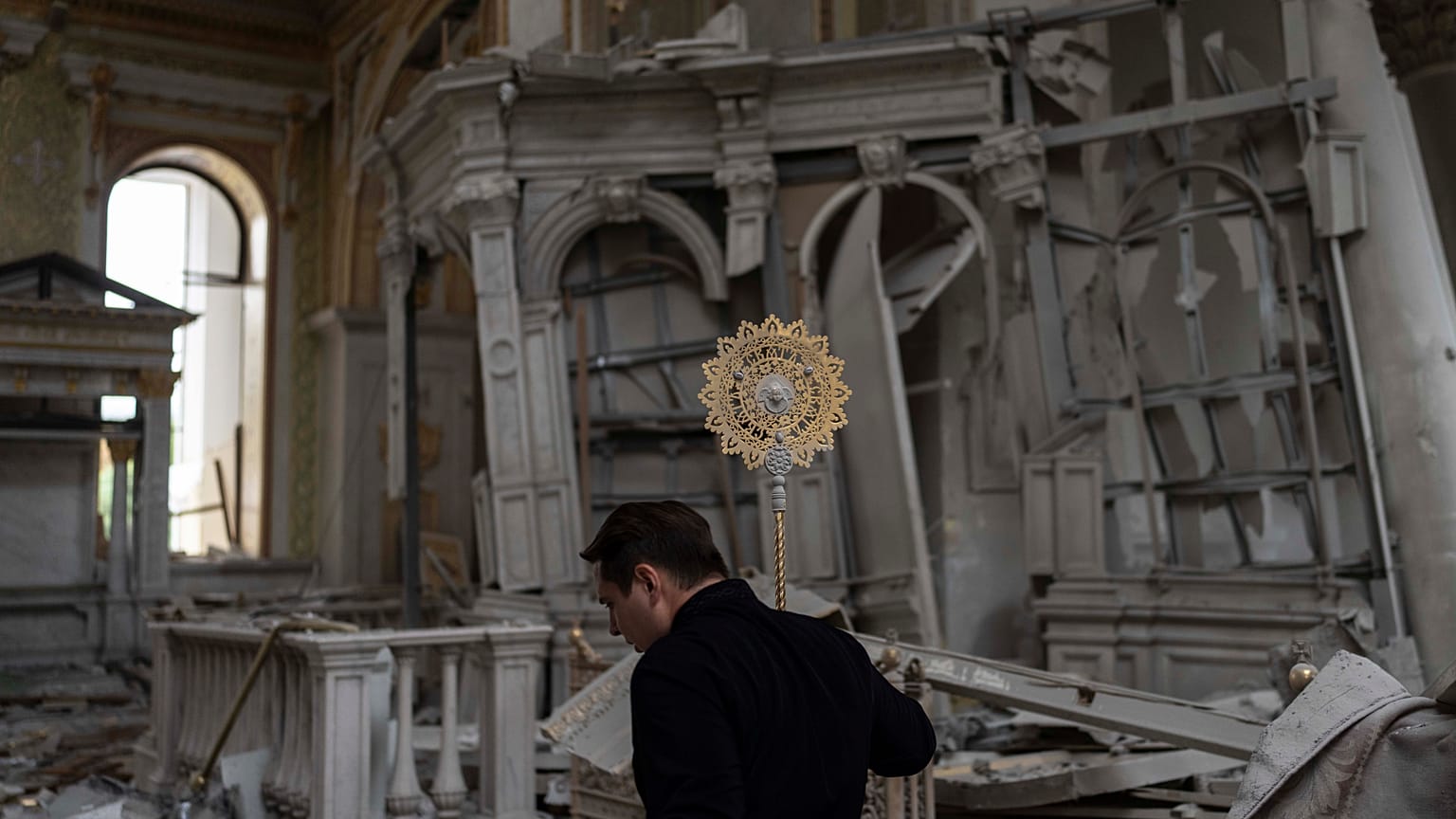A church personnel salvages items while helping clean up inside the Odesa Transfiguration Cathedral after it was heavily damaged in Russian missile attacks in Odesa, Ukraine