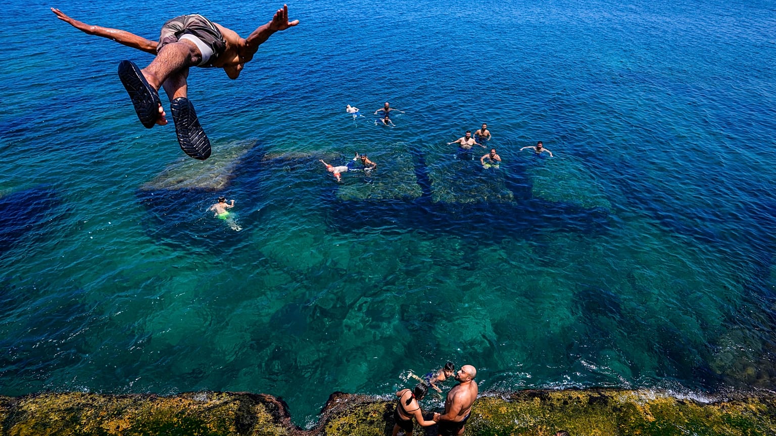 Um homem mergulha para as águas do Mediterrâneo em Beirute, Líbano