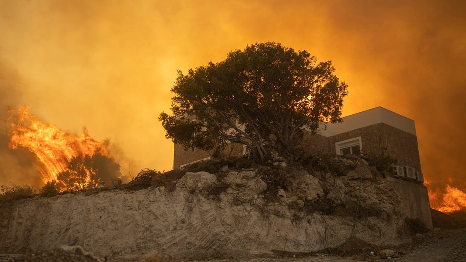 A local reacts as the flames burn trees in Gennadi village, on the Aegean Sea island of Rhodes, southeastern Greece, on Tuesday, July 25, 2023. 