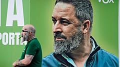 Un hombre junto a un cartel electoral del partido ultraderechista Vox en el que aparece su líder, Santiago Abascal, frente a la sede del partido en Madrid.