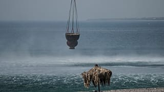 A helicopter fills water from the sea during a wildfire, near Gennadi village, on the Aegean Sea island of Rhodes, southeastern Greece, on Thursday, July 27, 2023.