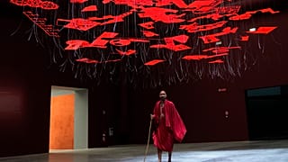A man wearing traditional Masai clothes walks under an installation, at the Biennale International Architecture exhibition, in Venice, Italy, Wednesday, May 17, 2023.