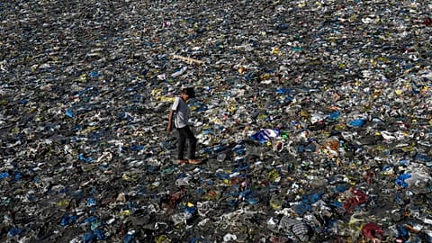 A boy walks on the plastic waste at the Badhwar Park beach on the Arabian Sea coast in Mumbai, India,