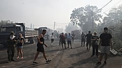 Residentes locales permanecen en la carretera durante un incendio forestal en la localidad de Nea Anchialos, cerca de la ciudad de Volos, Grecia central.