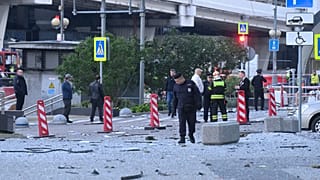 Investigators examine an area next to the damaged skyscraper in the "Moscow City" business district after a reported drone attack in Moscow, Russia, early Sunday, July 30, 202