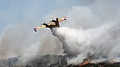 Um avião lança água sobre um incêndio florestal perto da cidade de Volos, no centro da Grécia, esta quinta-feira.