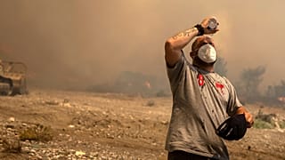 A volunteer cools himself during a wildfire in Vati village, on the Aegean Sea island of Rhodes, southeastern Greece.