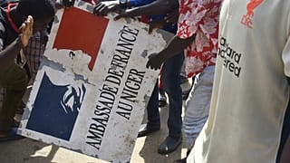 Protesters hold a sign taken from the French Embassy in Niamey during a demonstration that followed a rally in support of Niger's junta.