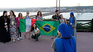 Католические паломники на фоне Моста 25 апреля в Лиссабоне