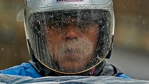 Rainwaters is seen on a windshield of a rider's helmet as he wades through a street in Beijing, Tuesday, Aug. 1, 2023.