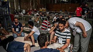 Survivors of a shipwreck sit inside a warehouse where are taking shelter at the port in Kalamata town, about 240 kilometers southwest of Athens, on Thursday, June 14, 2023.