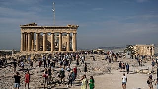 Turisti visitano la collina dell'Acropoli con il tempio del Partenone, vecchio di 2.500 anni, a sinistra, e l'antico tempio dell'Eretteo, a destra, ad Atene, in Grecia, l'11 ottobre 2022.