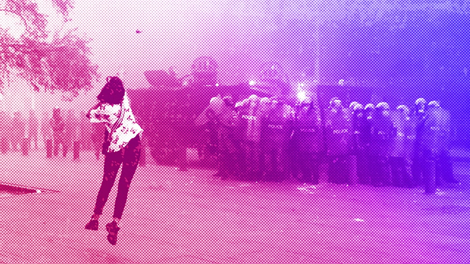 An anti-government protester woman throws a stone towards riot police during a protest near Parliament Square, in Beirut, September 2020