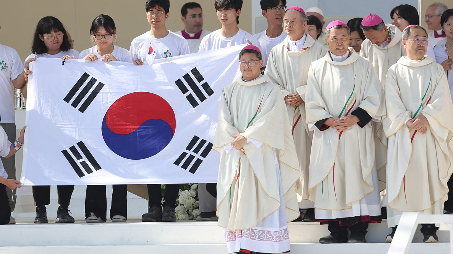 Peregrinos e bispos posam para fotografia, segurando bandeira sul-coreana, país que vai receber as próximas JMJ, durante missa de encerramento da JMJ, Lisboa, 6 de agosto 2023