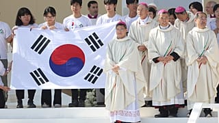 Peregrinos e bispos posam para fotografia, segurando bandeira sul-coreana, país que vai receber as próximas JMJ, durante missa de encerramento da JMJ, Lisboa, 6 de agosto 2023