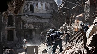 Donetsk People Republic Emergency Situations Ministry employees clear rubble at the side of the damaged Mariupol theater in Mariupol.