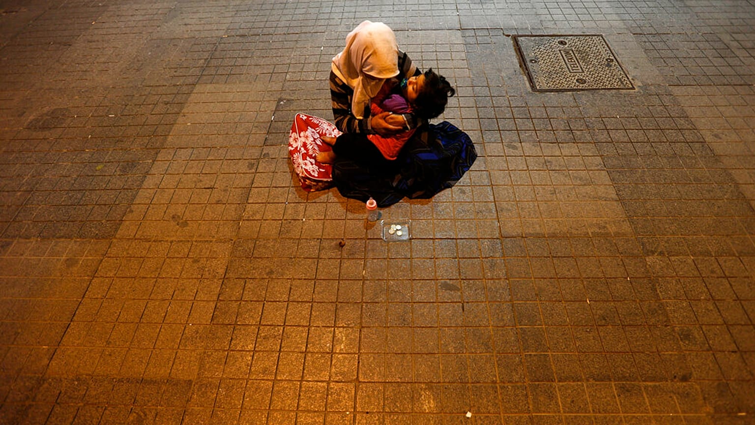 Une femme tient son enfant pour mendier de l'argent près de la place Taksim à Istanbul, Turquie, mardi 18 juin 2013\. 