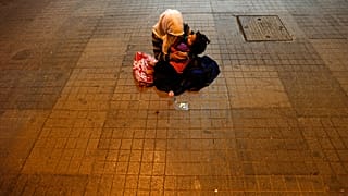 A woman holds her child to beg for money near Taksim Square in, Istanbul, Turkey, Tuesday, June 18, 2013.