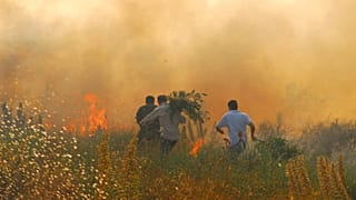 Nesta fotografia de julho de 2009, voluntários correm enquanto trabalham para apagar um incêndio florestal perto de Nuoro, no centro da Sardenha.