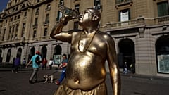 Una estatua viviente humana bebe de una botella mientras se toma un descanso durante una inusual ola de calor del periodo invernal en Santiago, Chile, 4 de agosto de 2023.
