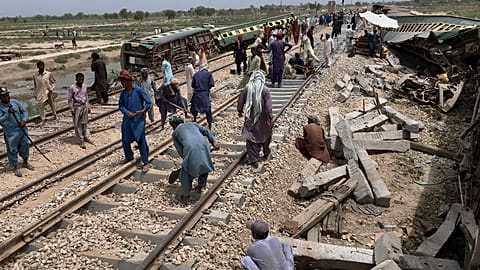 Des ouvriers réparent une voie ferrée sur le site de l'incident du train qui a déraillé dimanche, près de Nawabshah, un district de la province du Sindh, dans le sud du Pakist