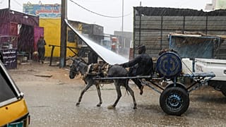 رجل يركب عربة يجرها حمار أثناء هطول أمطار غزيرة في منطقة سقاعي بالقرب من أم درمان، السودان، في 5 أغسطس 2023.