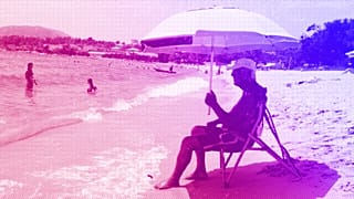 A man sits under the shade of a parasol on the Ricanto beach in Ajaccio, July 2023