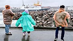 Menschen stehen bei windigem Wetter auf der Außenmole des Hafens von Hirtshals in Dänemark