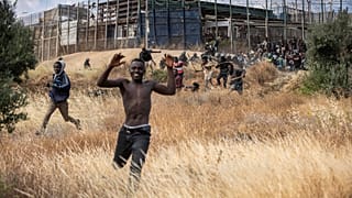 Migranti corrono sul suolo spagnolo dopo aver attraversato le recinzioni che separano l'enclave spagnola di Melilla dal Marocco a Melilla.