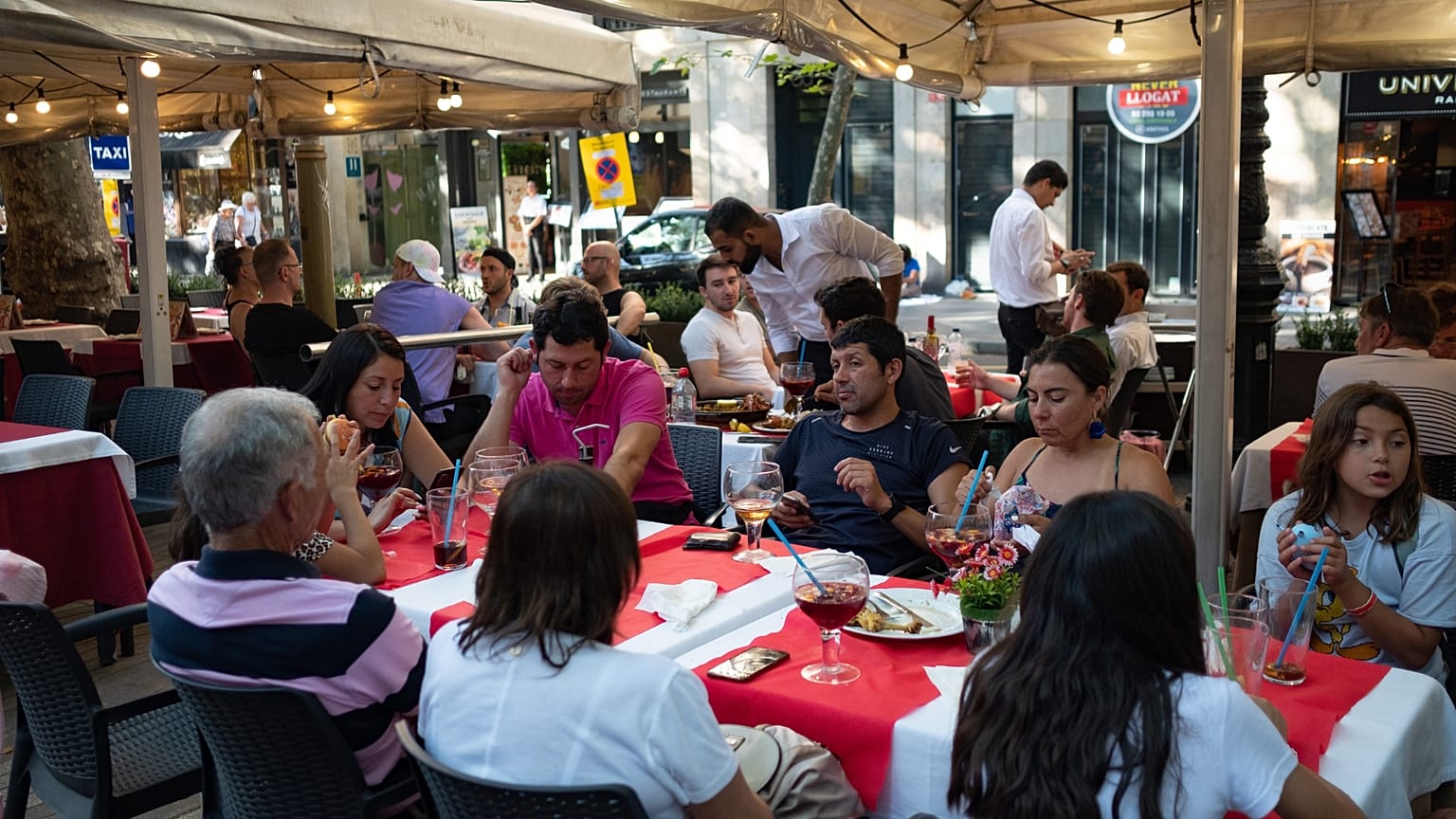 Touristen essen auf einer der beliebten Außenterrassen Barcelonas. 