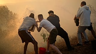 Vecinos utilizan cubos con agua para intentar frenar las llamas que se acercan a sus casas en Alcabideche, a las afueras de Lisboa. El 25 de julio de 2023.