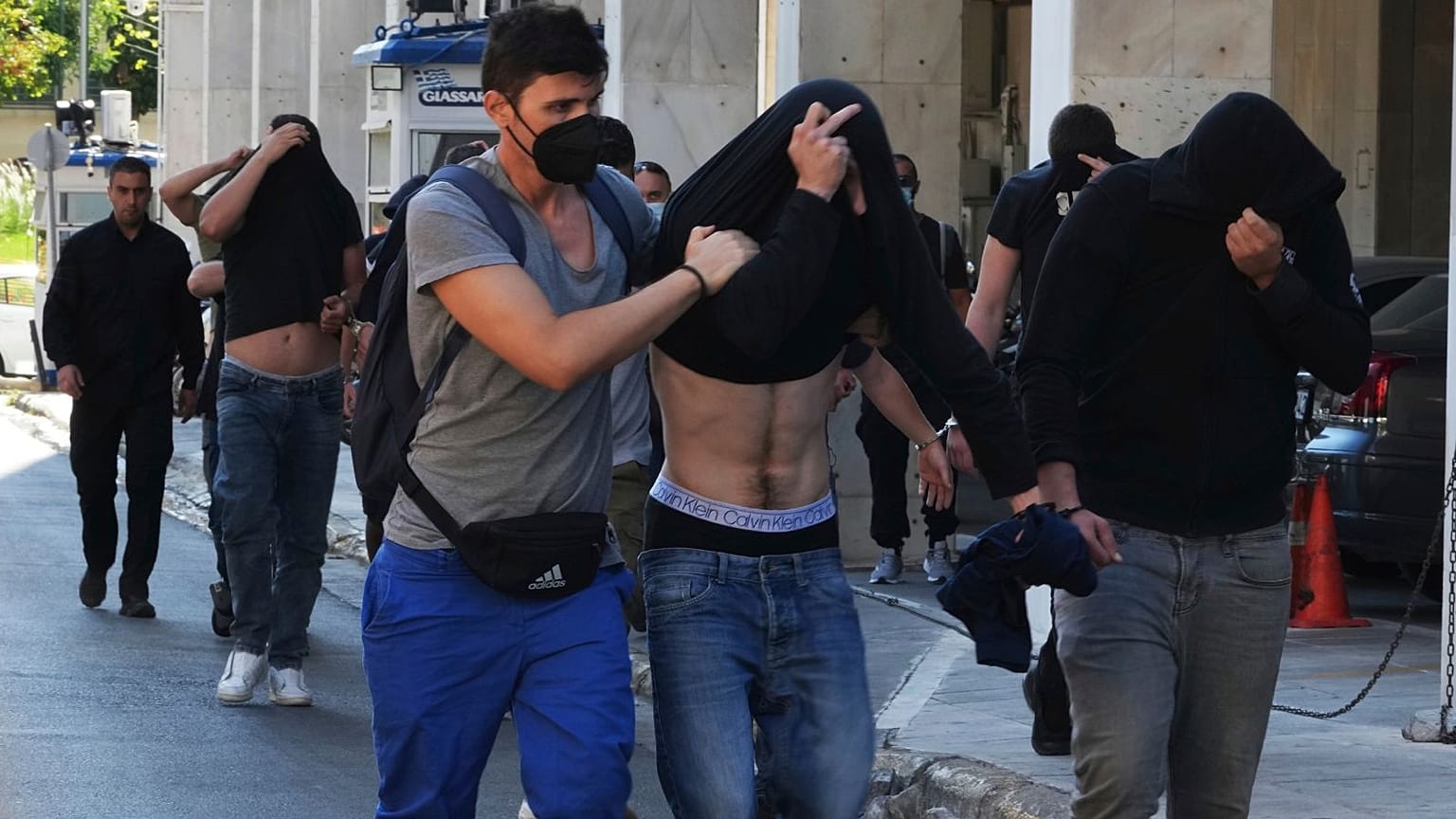 Football fans, mostly from Croatia, covering their faces as they are escorted by police from Athens Police Headquarters.