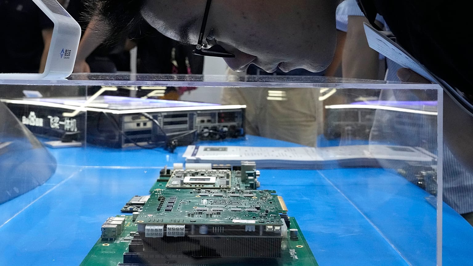 A visitor examines a computer chipset at the booth for Chinese semiconductor and chip developer Kunlunxin during the World AI Conference in Shanghai, Wednesday, July 5, 2023.