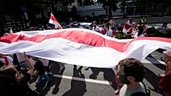 FILE - Protesters carrying the white-and-red banner of the Belarusian opposition march past the U.S. Embassy in Warsaw, Poland, on Sunday, Aug. 8, 2021. 