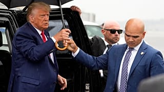 والت نوتا (يمين)، يحمل مظلة للرئيس الأمريكي السابق دونالد ترامب