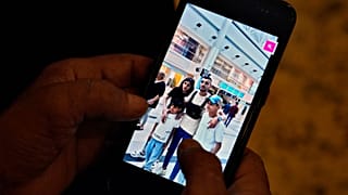 Mohamed Diab, the father of 21-year-old Abdulrahman, centre, who was on the boat that sank off the coast of Greece, holds a phone showing a photo of his sons.