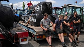 Protesting farmers talk at a blockade outside a distribution centre for supermarket chain Aldi in the town of Drachten, northern Netherlands, on 4 July 2022.