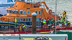 Paramedics assist a migrant picked up at sea while attempting to cross the English Channel, after they were picked up by a British lifeboat.
