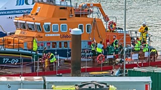 Paramedics assist a migrant picked up at sea while attempting to cross the English Channel, after they were picked up by a British lifeboat.