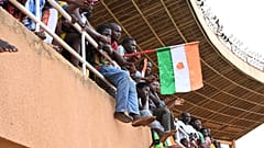 A man waves a Nigerien flag as supporters cheer from the stands while artists perform during a concert in support to Niger's National Council for the Safeguard of the Homeland