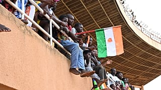 A man waves a Nigerien flag as supporters cheer from the stands while artists perform during a concert in support to Niger's National Council for the Safeguard of the Homeland