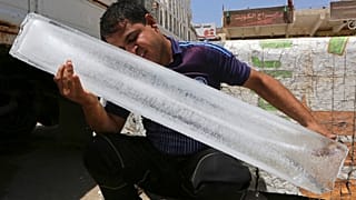رجل يبرد وجهه بعد شراء قطعة ثلج في البصرة بما يعادل 4 دولارات