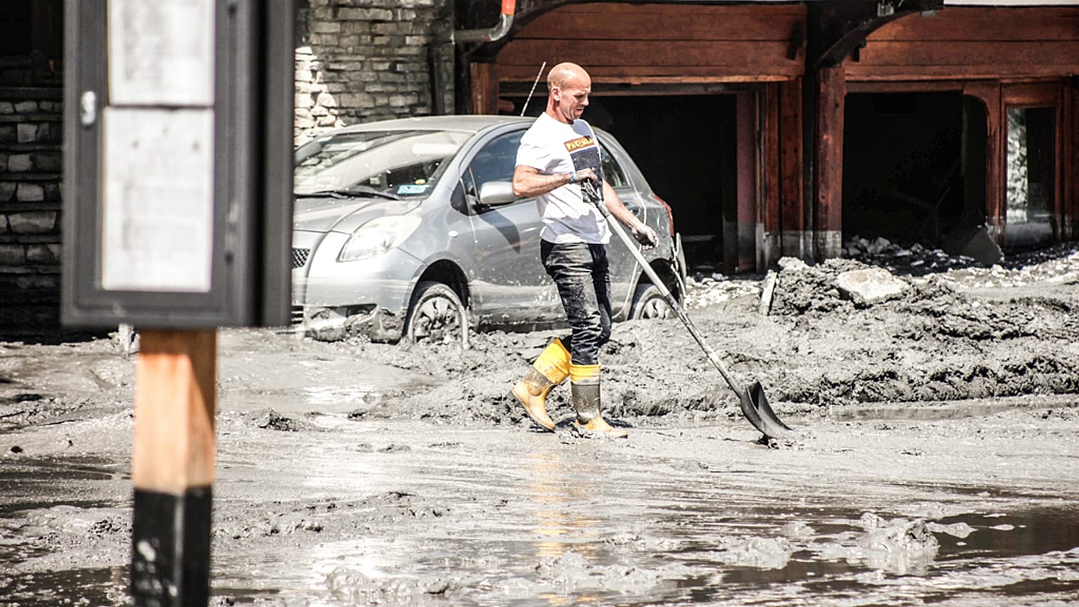 A resident clears mud and debris covering the streets, following a mountain mudslide, which caused the flooding of a stream in Bardonecchia.