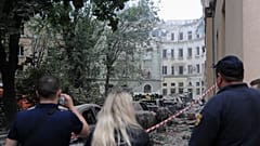 Varias personas observan cómo los trabajadores de los servicios de emergencia continúan buscando víctimas tras un ataque con misiles rusos en Leópolis, el 6 de julio de 2023.
